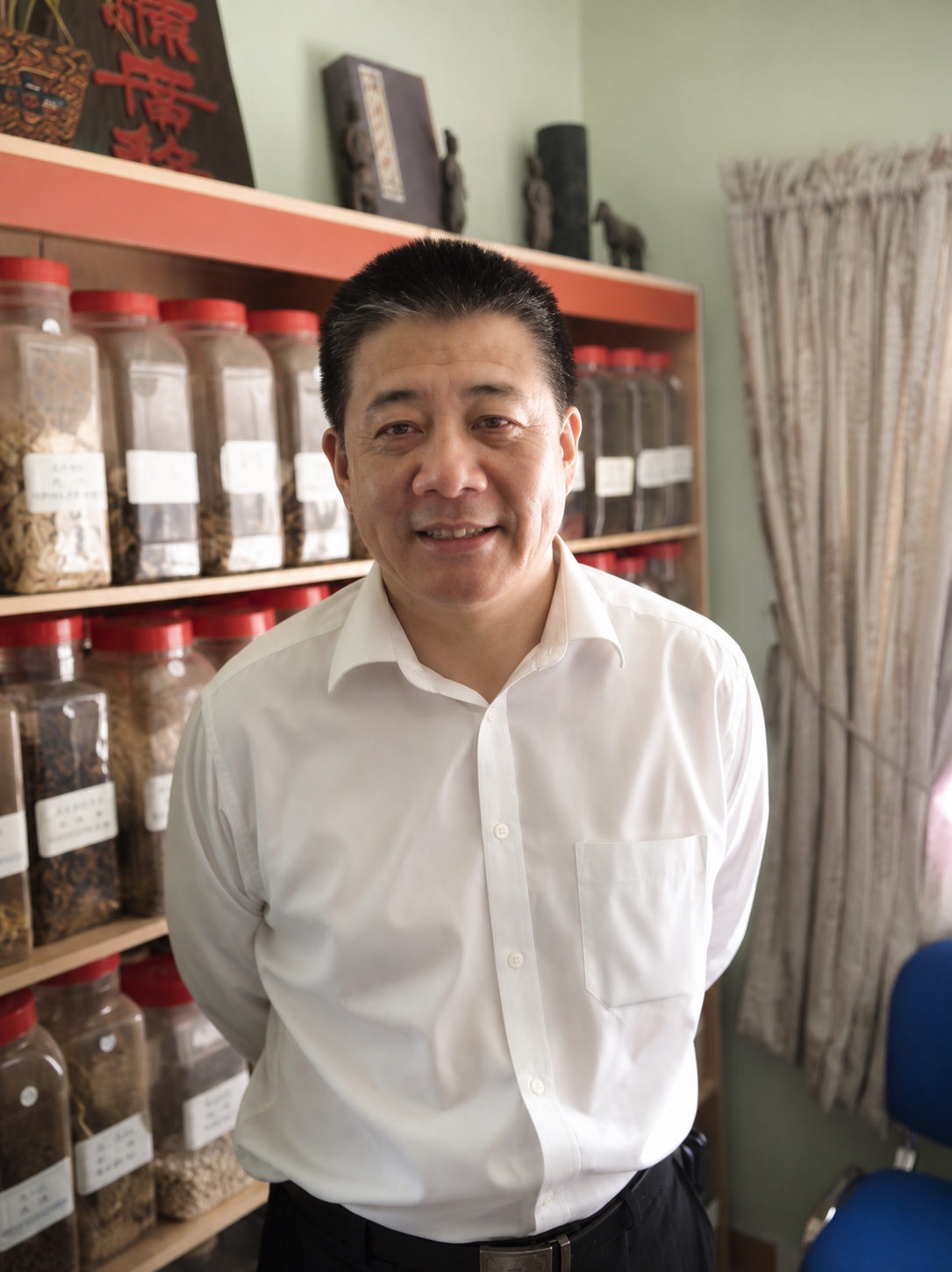 Dr Shi in the clinic's dispensary, in front of the herb jars